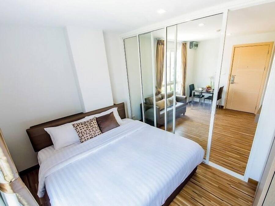 Een hotelkamer met een groot bed, een glazen scheiding en uitzicht op een eetruimte.
