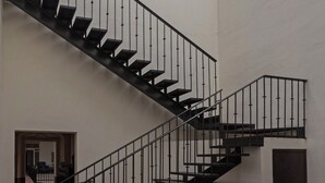 Un interior de varios niveles con una escalera central, tragaluces y suelo de baldosas.