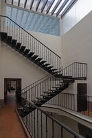 Een meerlaags interieur met een centrale trap, dakraam en betegelde vloer.