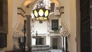 Un hall de hotel con una espectacular lámpara de araña, una fuente y un banco.
