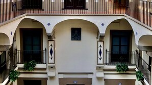 Un edificio de varios niveles con balcones, arcos y plantas colgantes.