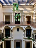 Een gebouw met meerdere verdiepingen, balkons, gebogen deuropeningen en hangende planten.