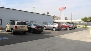 A parking lot with several cars parked in front of a building with a sign that reads "EMPIRE". - Four Corners motel (Montebello)