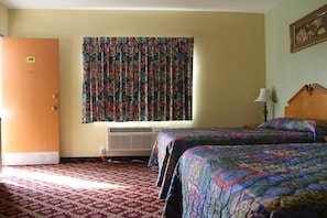 A hotel room with two beds, a floral curtain, an air conditioning unit, and a door marked with the number 116. - Four Corners motel (Montebello)