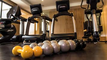 Un gimnasio con equipo de ejercicio que incluye cintas de correr, elípticas y mancuernas.