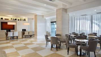 A hotel lobby with a checkered floor, multiple seating areas, a flat-screen TV, and a modern design.