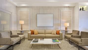 A modern living room with a beige sofa, two armchairs, a coffee table, and two side tables with lamps.