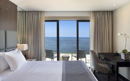 A hotel room with a bed, a desk, and a view of the ocean.