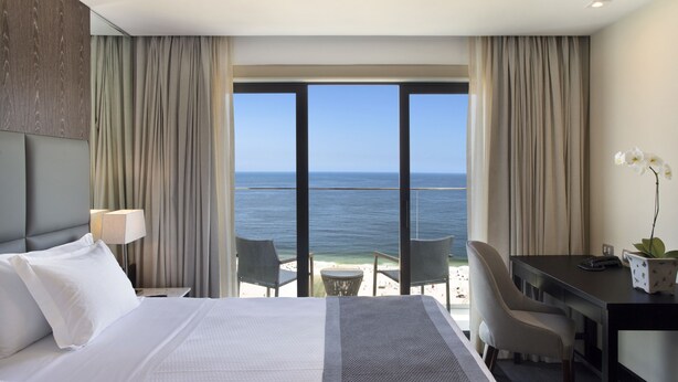 Une chambre d’hôtel avec un lit, un bureau et une vue sur l’océan.