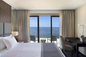 A hotel room with a bed, a desk, and a view of the ocean.