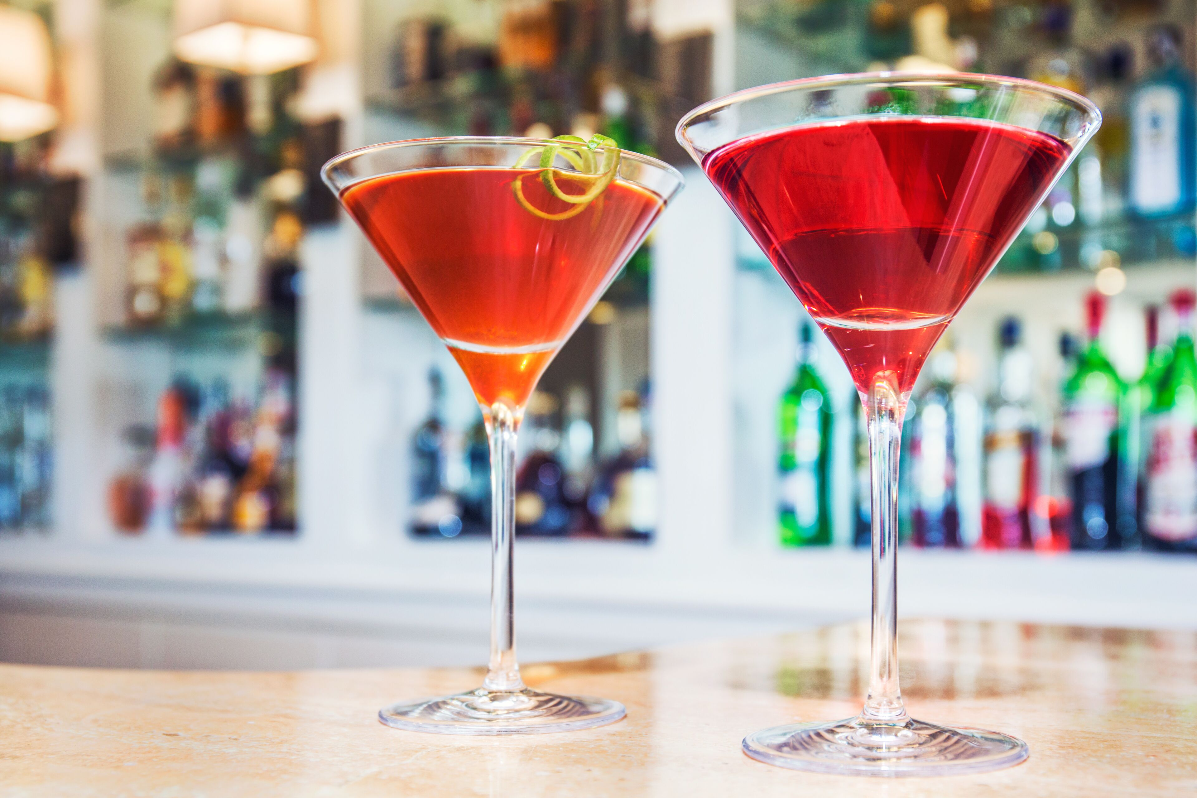 Deux verres à martini contenant des cocktails rouges, posés sur le comptoir d’un bar.