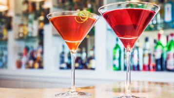 Two martini glasses with red cocktails on a bar counter.
