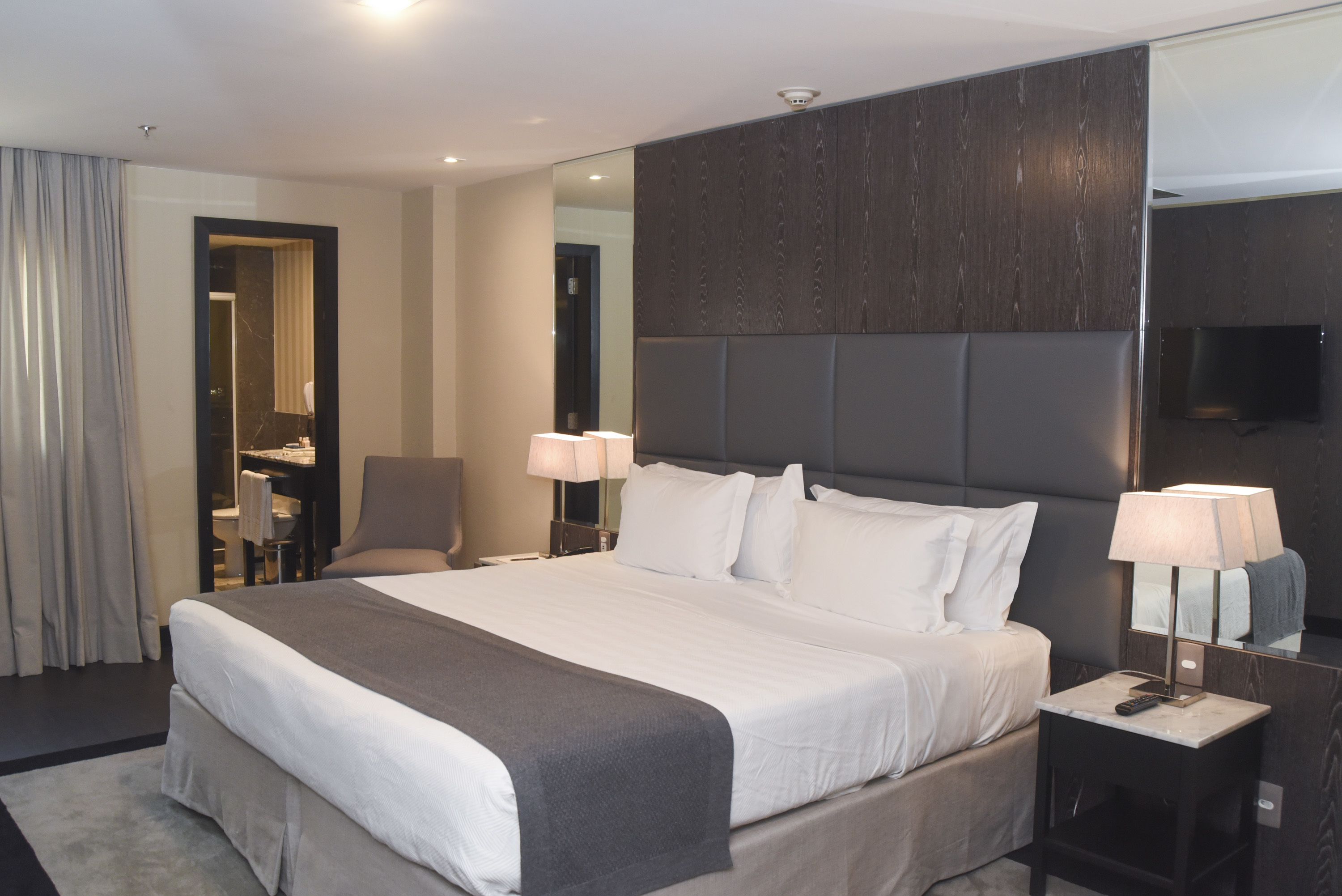 Een moderne hotelkamer met een groot bed, een bureau en een televisie.