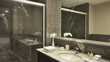 A modern bathroom with a marble vanity, a large mirror, and a sink.
