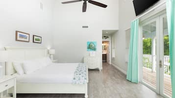 A bedroom with a bed, nightstands, a ceiling fan, a painting, and a view of the outdoors through a sliding glass door.