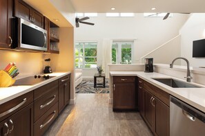 A modern kitchen with dark wood cabinets, stainless steel appliances, and a large window providing a view of the outdoors.
