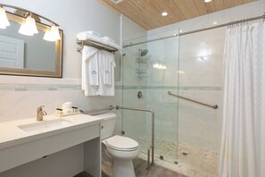 A modern bathroom with a glass shower enclosure, a white sink, and a toilet.