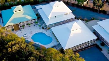 Una piscina al aire libre, sombrillas, sillones reclinables de piscina