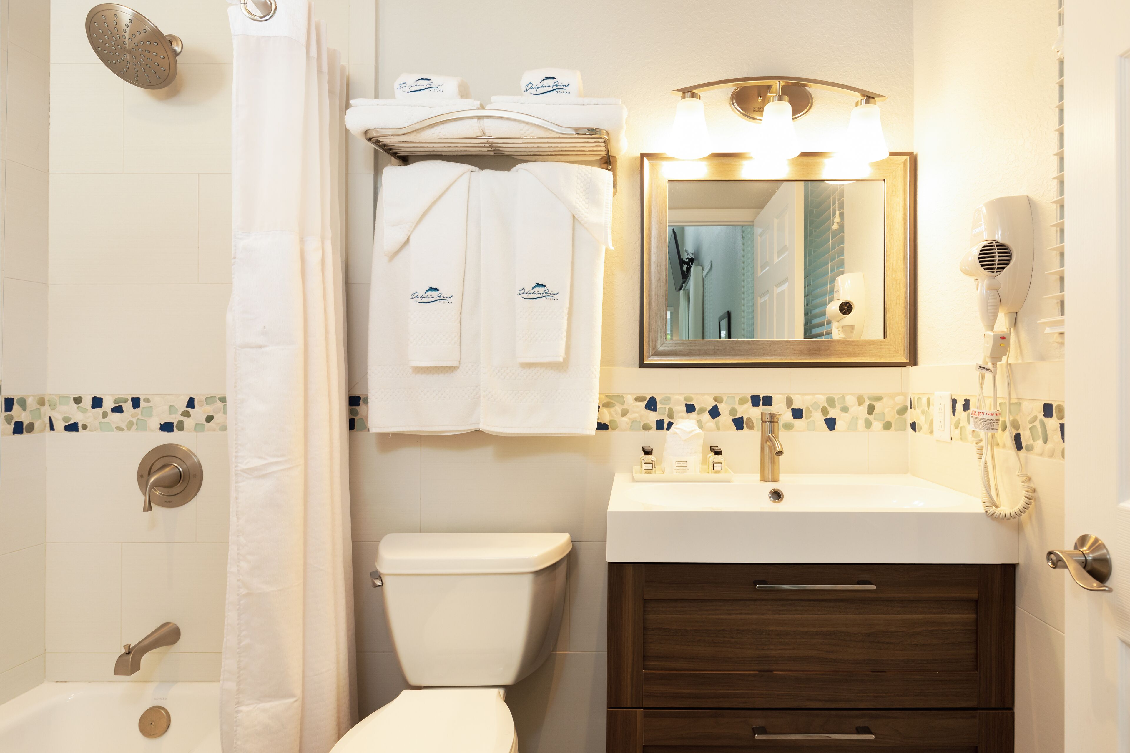 A bathroom with a shower, toilet, sink, and vanity.