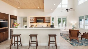 Una cocina moderna con armarios de madera, una isla central con taburetes y un ventilador de techo.