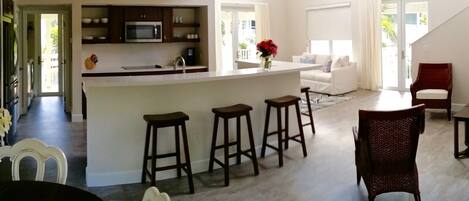 Un grand espace de vie comprenant une cuisine, une table à manger et un coin bar avec des tabourets.