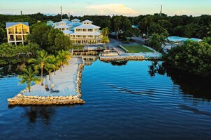 A waterfront property with multiple buildings, a dock, and a small island with palm trees.
