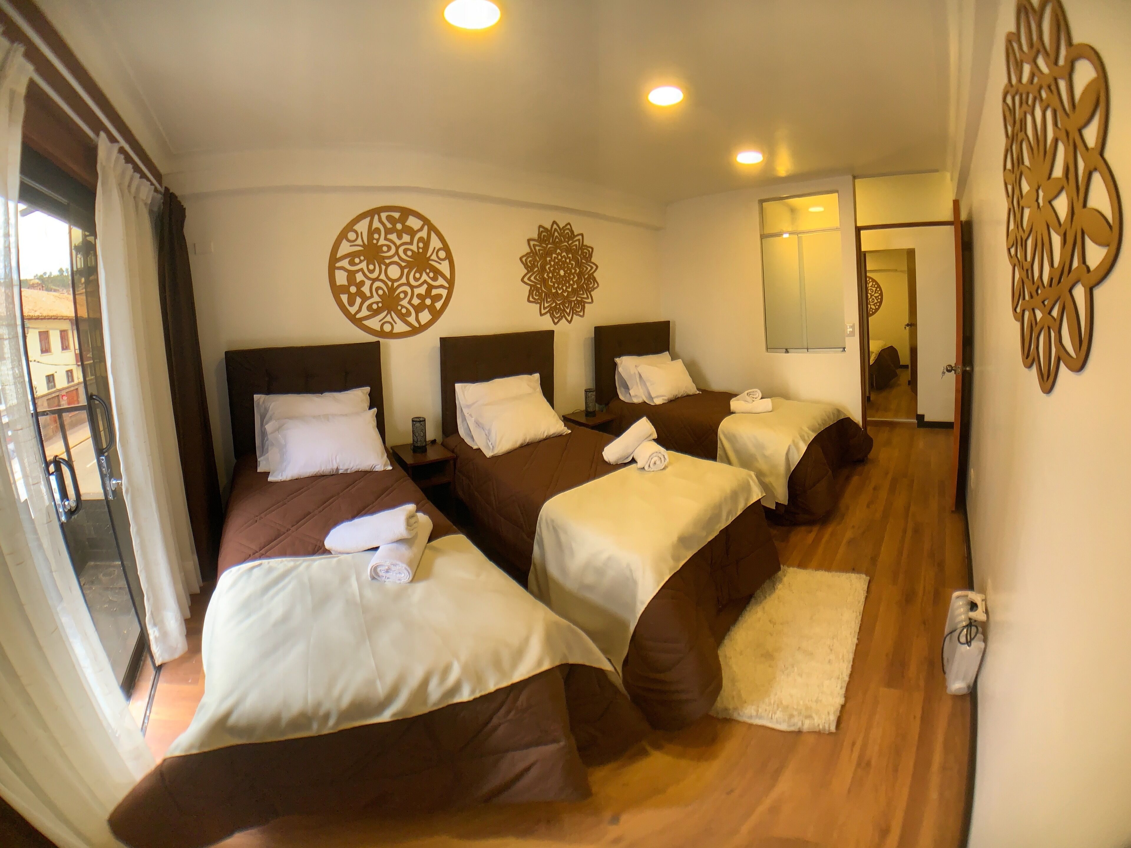 A hotel room with four beds, a balcony, and decorative wall art.