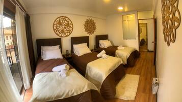 A hotel room with four beds, a balcony, and decorative wall art.