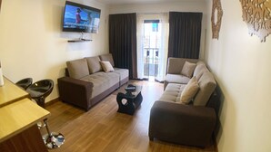 A living room with two sofas, a coffee table, and a TV mounted on the wall. - Del Niño Apartments (Cusco)