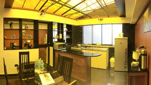 A compact kitchen with a dining area, featuring a glass table, chairs, and a small island with a stove. - Del Niño Apartments (Cusco)