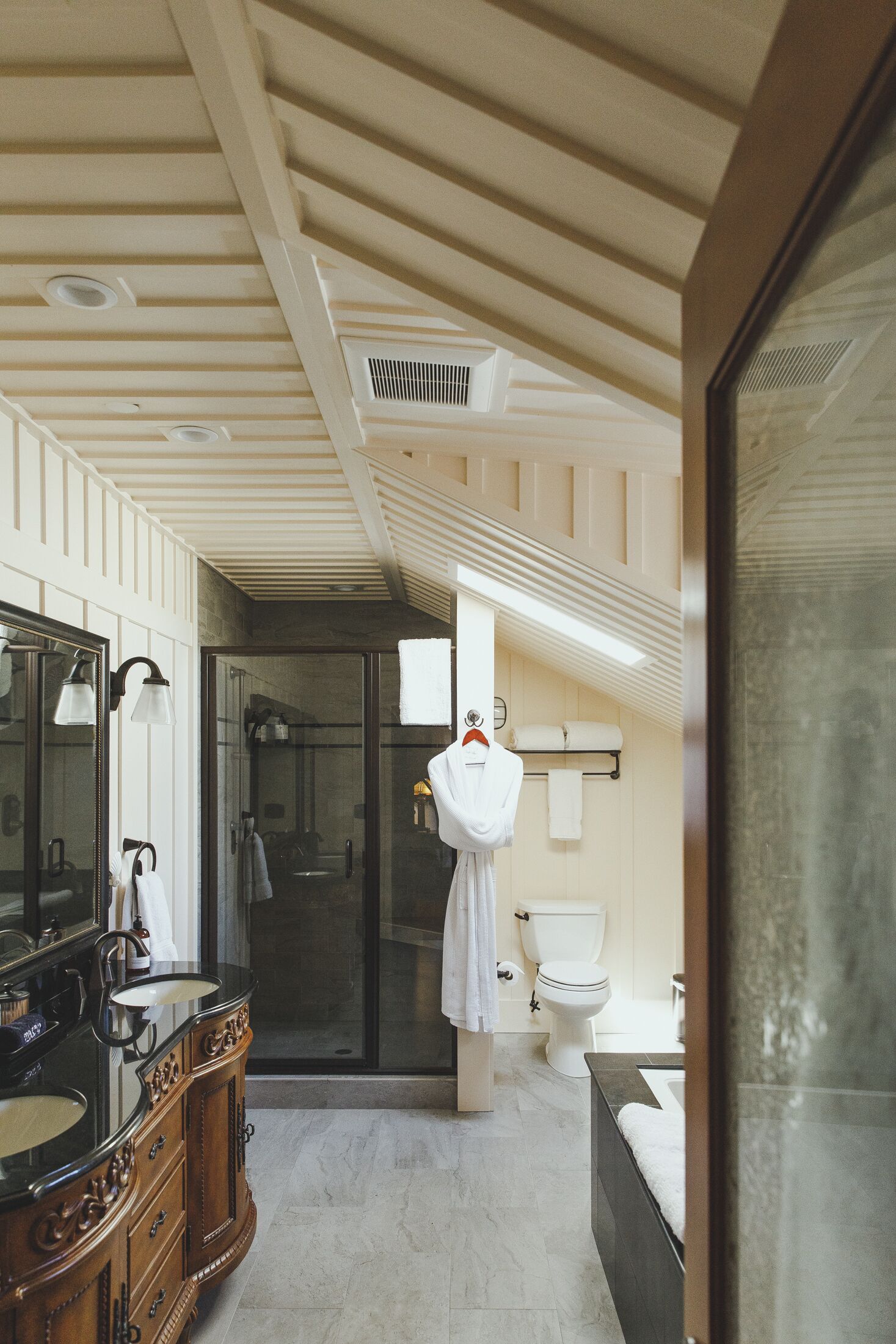A modern bathroom with a vanity, a large mirror, a glass shower enclosure, and a toilet.
