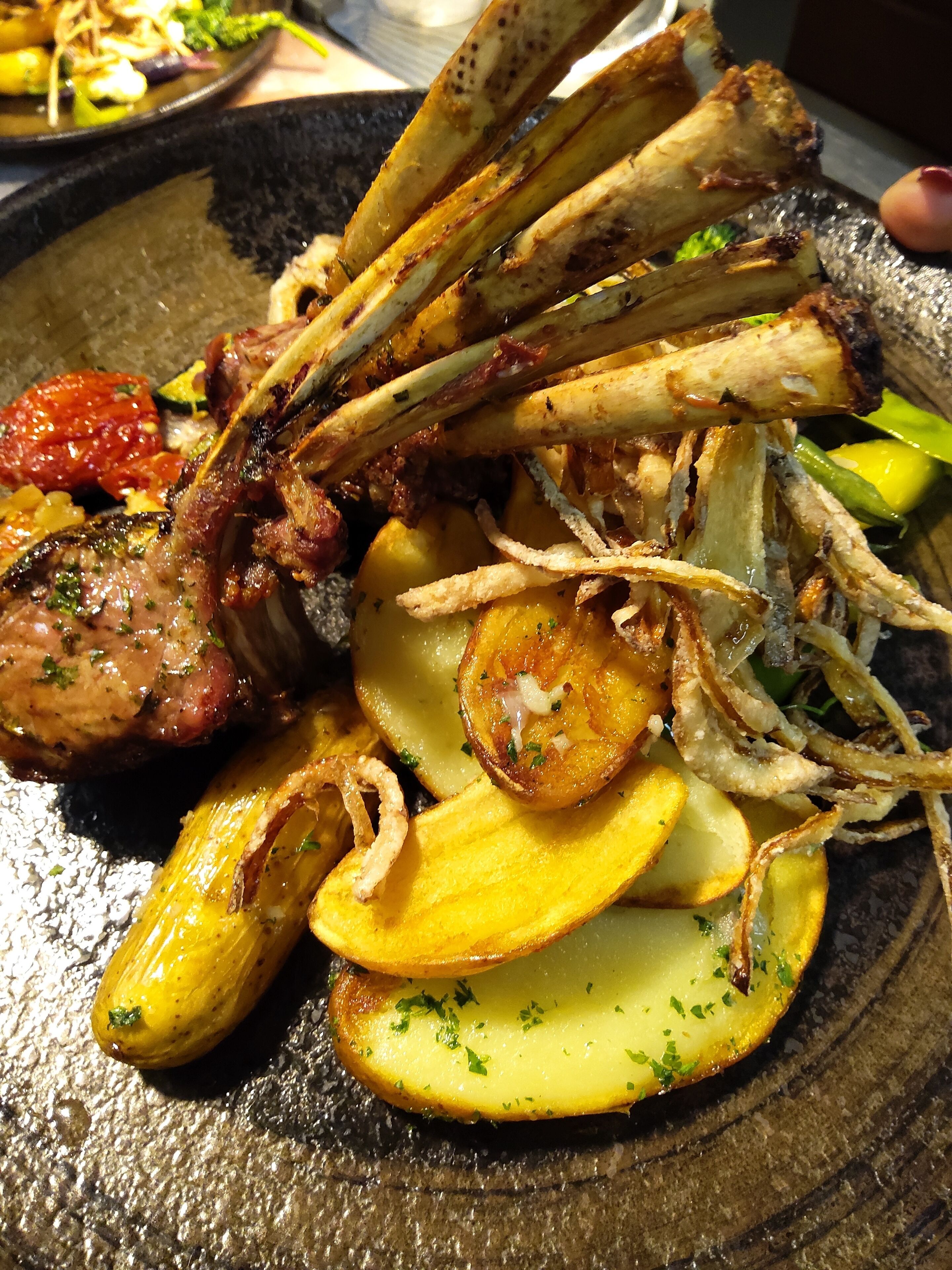 A plate of food with roasted potatoes, grilled meat, and a side of sauce.