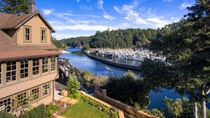 A two-story building with a large bay window, a staircase leading to a deck, and a view of a marina with boats docked along a river. - Noyo Harbor Inn Restaurant and Tavern (Fort Bragg)