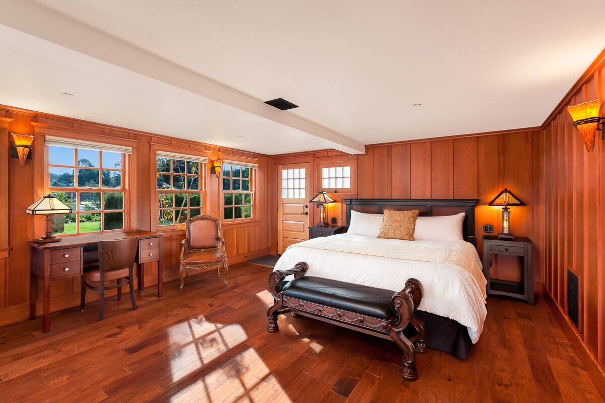 A spacious bedroom with a large bed, wooden walls, and a desk with a chair.