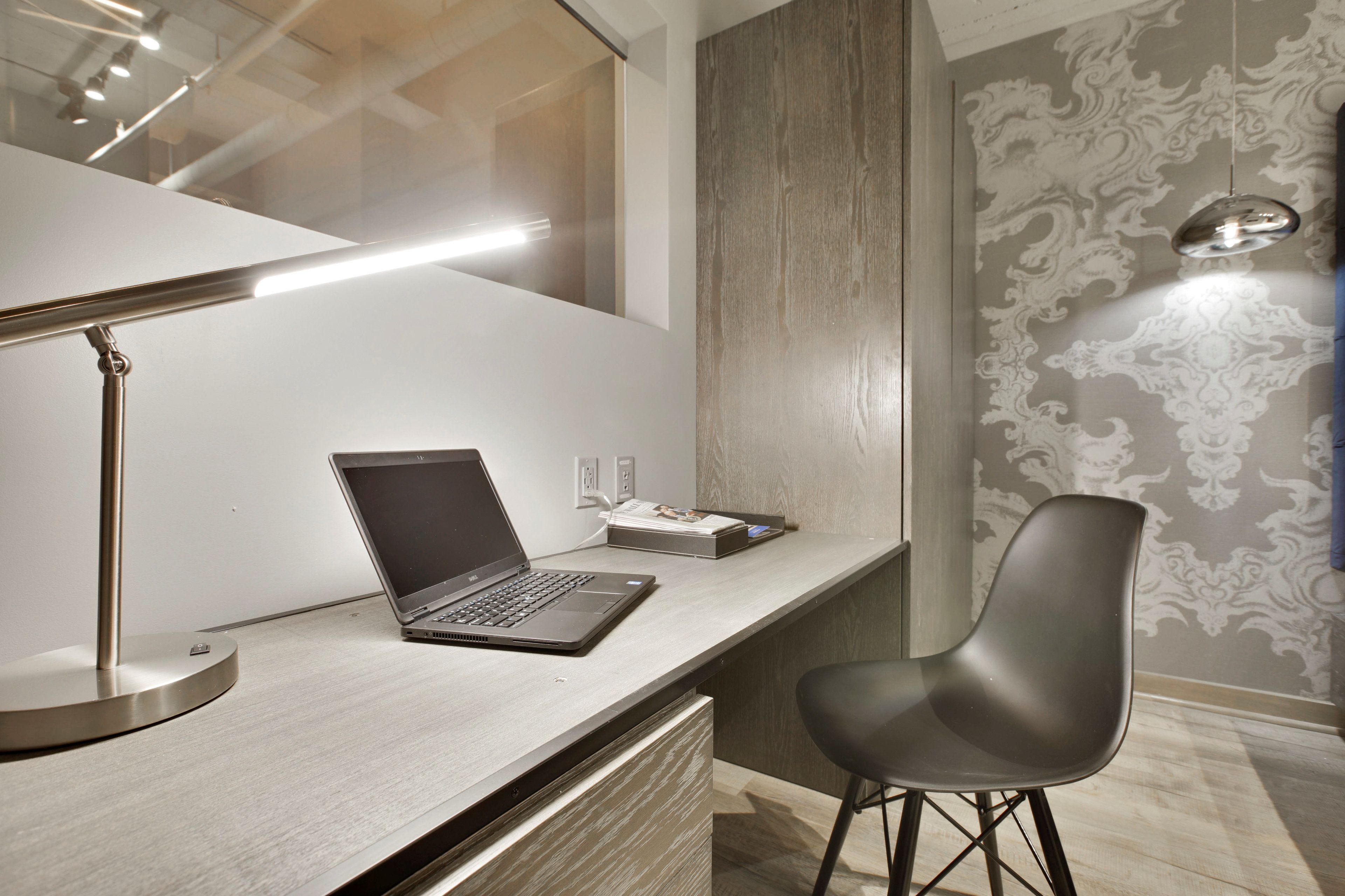 A modern workspace with a laptop on a desk, a chair, and a desk lamp.