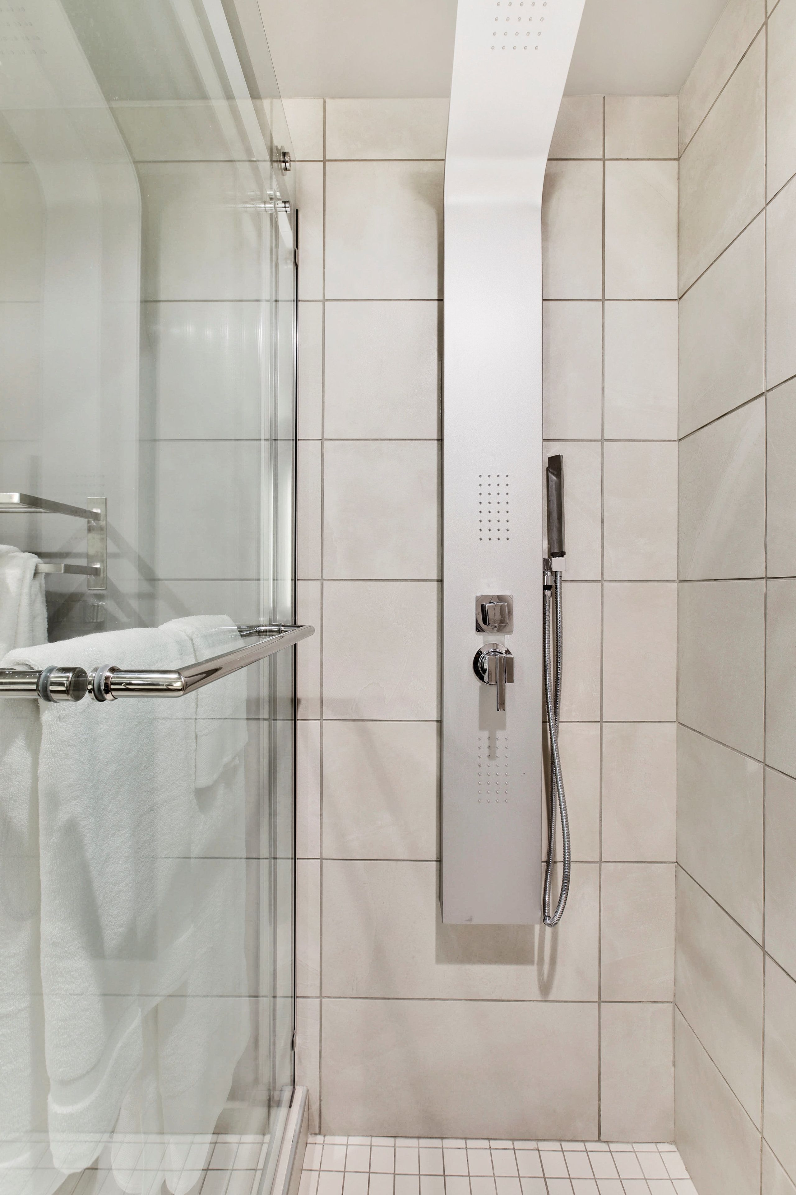 Una ducha moderna con cabina de vidrio, un perchero y un panel de control.