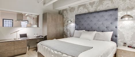 A modern bedroom with a large bed, a desk, and a wardrobe.
