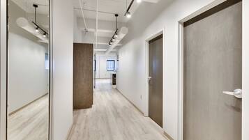 A corridor with wooden flooring, white walls, and a door on the right.
