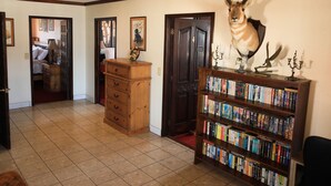 Un pasillo con una estantería de madera, una puerta y una habitación al fondo.
