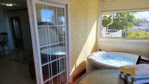 Una habitación con mesa de vidrio, bañera de hidromasaje y vistas al exterior.