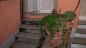 A staircase leading to a door with a window, a plaque on the wall, and potted plants. - Bed & Breakfast del Teatro (Cagli)