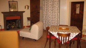 A cozy dining area with a table set for four, a sofa, and a fireplace. - Bed & Breakfast del Teatro (Cagli)