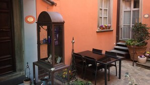 A cozy outdoor seating area with a table and chairs, a decorative cabinet, and potted plants. - Bed & Breakfast del Teatro (Cagli)