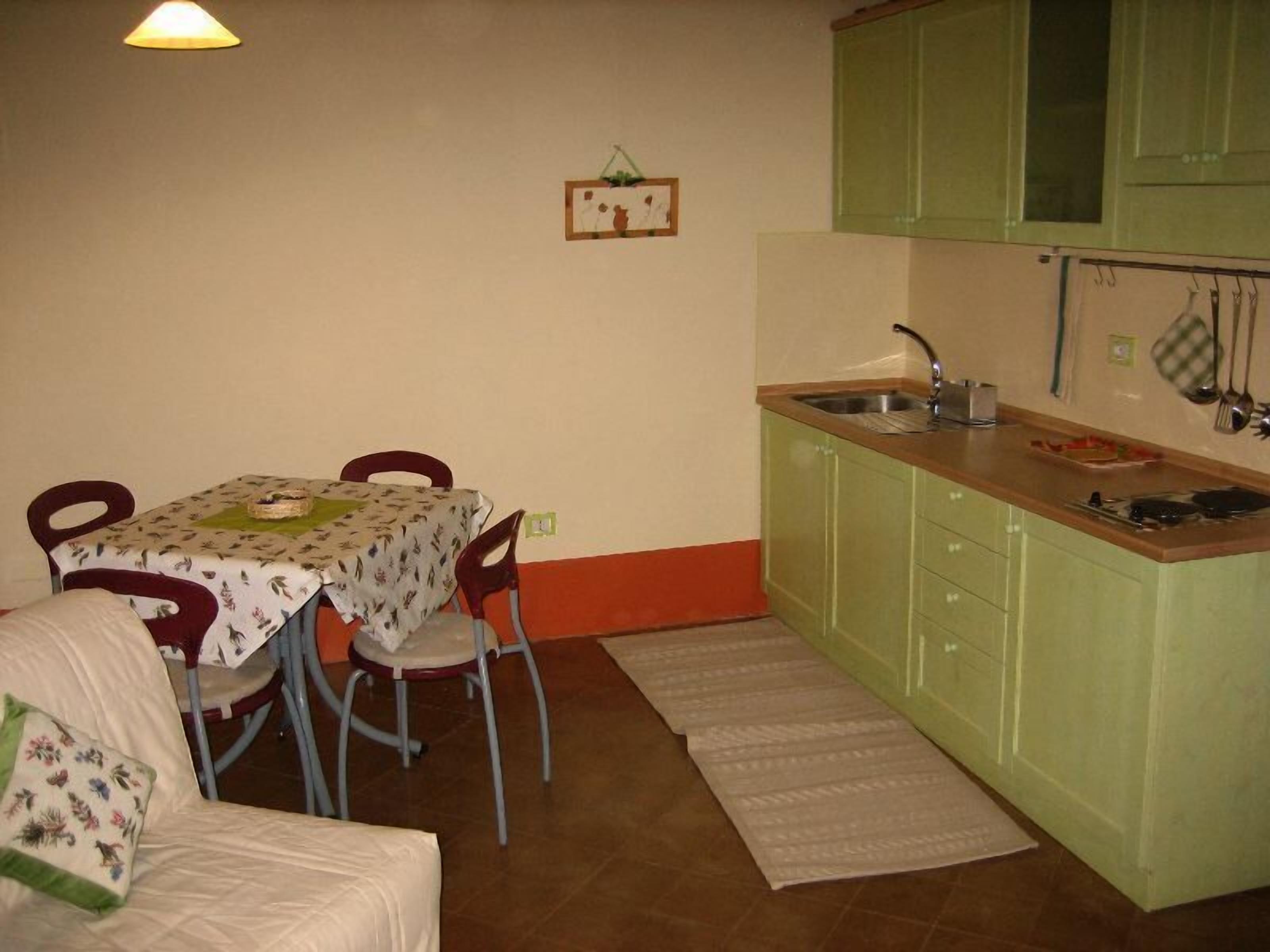 A small kitchen with a table and chairs, a sink, and green cabinets.