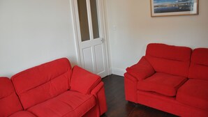 A room with two red sofas and a white door.