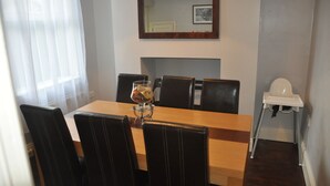 A dining area with a wooden table, black upholstered chairs, a white high chair, and a globe on the table.