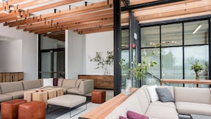 A modern lounge area with a wooden ceiling, a large window, and a seating arrangement including sofas and ottomans. - Harmon Guest House (Healdsburg)