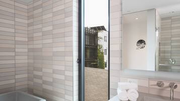 A modern bathroom with a large bathtub, a sink, and a mirror.