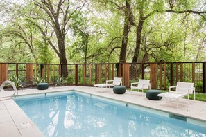 A swimming pool with lounge chairs and a wooden fence. - Harmon Guest House (Healdsburg)