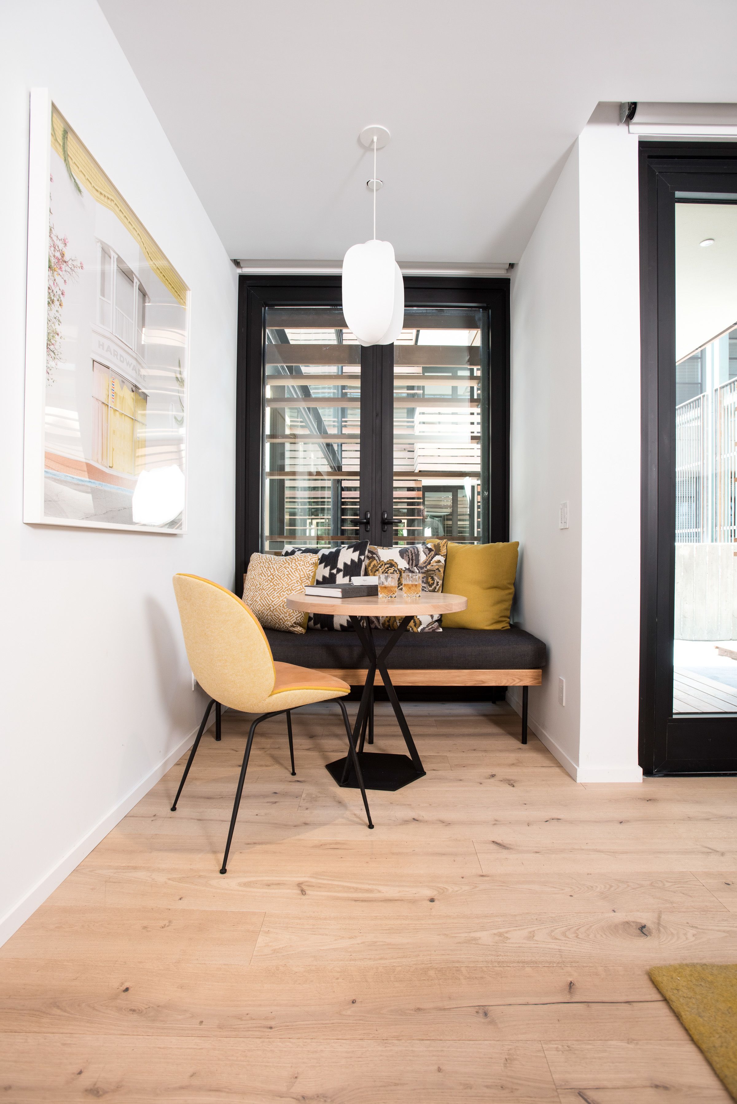 A modern dining area with a wooden floor, a round table, and a bench with cushions.